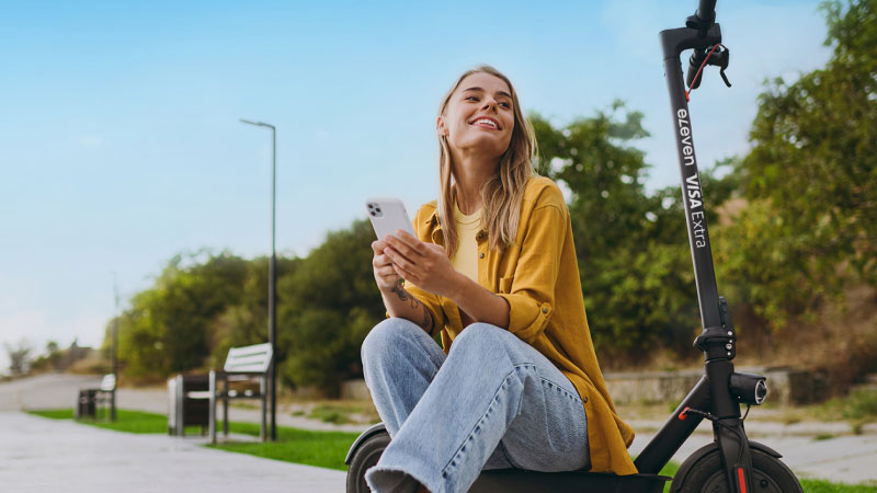 Человек с телефоном сидит на самокате